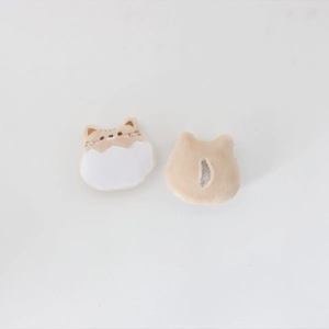 Detailed close-up of cute plush animal brooch accessories in beige and white