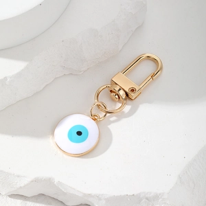 Golden alloy Evil Eye keychain charm with blue enamel detail on minimalist stone base