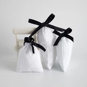 Minimalist white cotton drawstring jewelry pouches with elegant black ribbon bow in three sizes