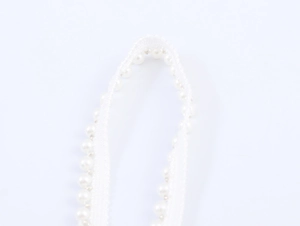 Close-up of white lace shoulder strap with delicate faux pearl beads for dresses