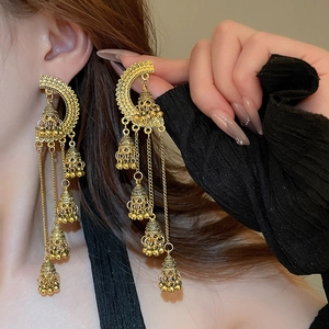 Boucles d'oreilles dorées à pompons et cloches boho portées pour un style élégant