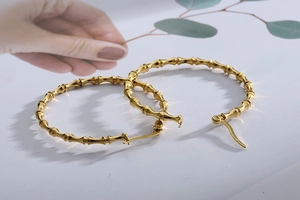 Detailed macro view of large gold bamboo textured hoop earrings with a secure clasp