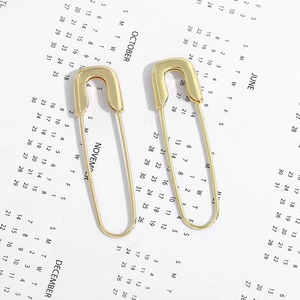 Minimalist gold paperclip earrings displayed on an aesthetic English calendar background
