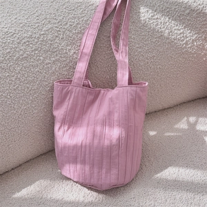 Detalle de bolso tote rosa plisado en un sofá mostrando los suaves pliegues de la tela