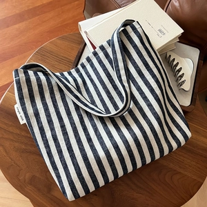 Detail of blue and white striped canvas tote bag with woven label on a wooden table