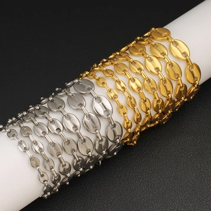 Detail of 18K gold and silver coffee bean link chains on white cylinders