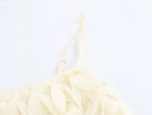 Detail of a beige camisole top featuring 3D floral petals and adjustable spaghetti straps