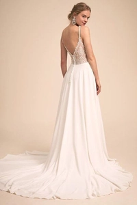 Detail showing the elegant backless design with delicate lace embroidery and buttons on a white bridal gown