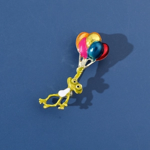 Vue détaillée de l'épingle en émail grenouille tenant des ballons colorés sur fond bleu