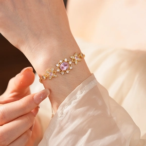 Detail of vintage gold bracelet with pink oval gemstone and floral links on wrist