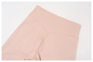 Detail of high waist yoga pants featuring V-shaped stitching in soft peach pink fabric