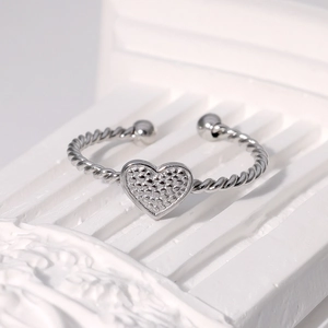 Close-up of heart-shaped ring with beaded texture and twisted rope band design