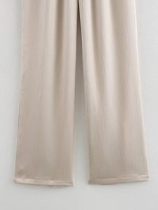 Détail du pantalon large plissé champagne avec fini satiné et texture de tissu noble
