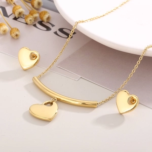 Detail shot of golden heart pendant necklace and earrings set on a white decorative plate