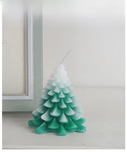 Detailed view of cedar-scented green and white gradient Christmas tree candle with snow texture