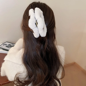 Detail of soft white plush claw clip securing a low ponytail on a female model