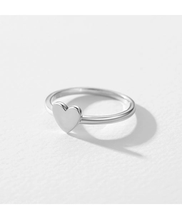 Macro shot of polished silver heart-shaped ring on textured white paper background