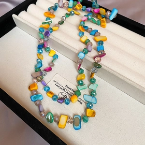 Détail d'un collier bohème avec des coquillages colorés et perles en cristal en boîte