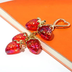 Detailed shot of golden keychain featuring four red transparent strawberry pendants