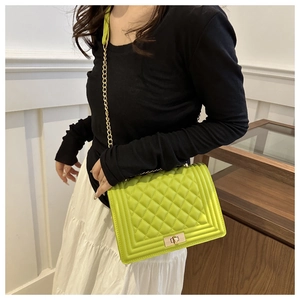 Close-up of grass green quilted PU leather shoulder bag with gold chain and metal lock