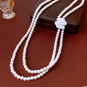 Detail of double-layer glass pearl necklace with white camellia flower pendant on vintage desk