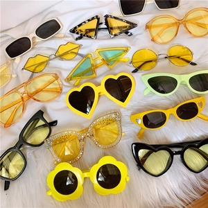 Flat lay of colorful flower and heart shaped sunglasses on white plush fabric