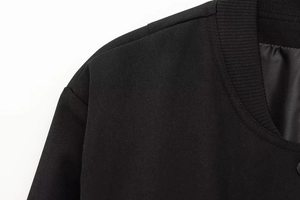 Detail der schwarzen Jacke mit Köperstoffstruktur und geripptem Kragenansatz