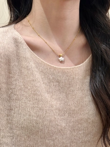 Collier avec pendentif étoile en nacre sur mannequin avec pull en maille rose doux