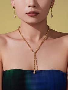 Mannequin portant collier en Y à billes dorées et boucles d'oreilles en zircon goutte