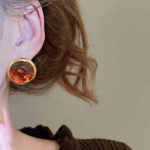 Macro side view of vintage round stud earring with amber resin stone and golden metal edge