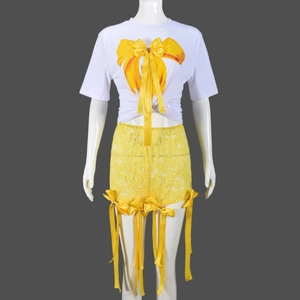 Détail du t-shirt blanc et du short en dentelle jaune avec des nœuds papillons en 3D