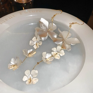 Detail of long fringe earrings with white matte floral petals and gold bead centers