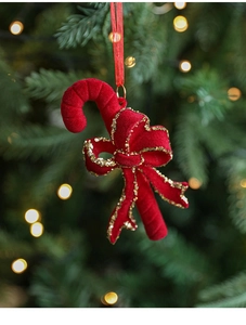 Detail of red velvet candy cane ornament with gold glitter bow on a Christmas tree