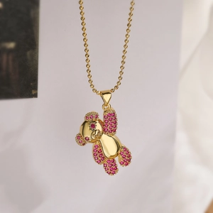 Détail macro du pendentif ours doré serti de zircons roses sur une chaîne à billes