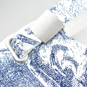 Close-up of blue and white tie-dye fabric with adjustable metal buckle and strap loop