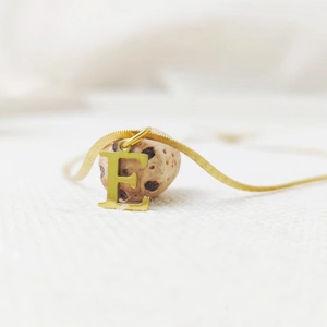 Close-up of a gold-plated titanium steel letter E initial necklace with a flat snake chain