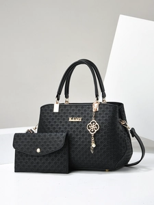 Fashionable black woven texture handbag and matching wallet with gold logo on a studio set