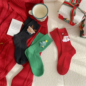 Close-up of 3D Christmas plush dolls on knitted crew socks including reindeer and Santa