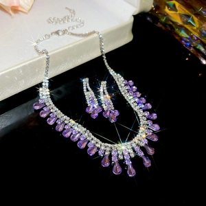 Detail of luxury necklace and earrings set with purple teardrop crystals and silver rhinestones