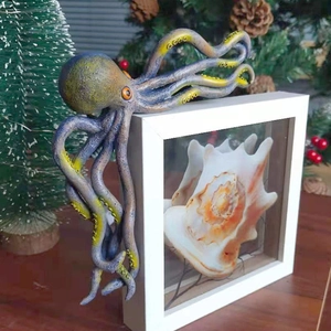 Detail of octopus sculpture and conch shell specimen inside a modern white photo frame