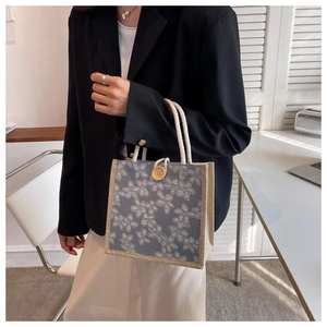 Close-up of gray floral canvas tote bag with cotton rope handles and wood button