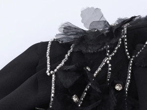 Détail d'une robe noire avec perles en strass et appliques florales 3D sur tulle mesh