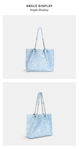 Detail view of light blue denim texture tote bag with silver chain straps and metallic accents