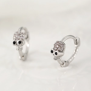 Macro shot of silver gothic skull earrings with white zircon pavé and black gem eyes