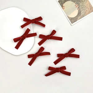 Detailed view of six red velvet ribbon hair clips neatly arranged on a white background