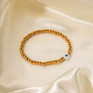 Détail de perles en acier inoxydable 18k et breloque œil bleu sur de la soie