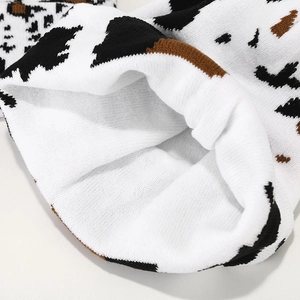Detail of thick cow pattern knit beanie showing soft white lining and woven texture