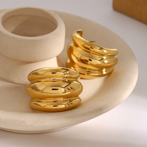 Macro shot of gold chunky earrings with ribbed texture on artistic ceramic plate