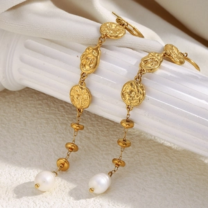Detail of 18K gold-plated hammered metal earrings with long tassels and white pearls