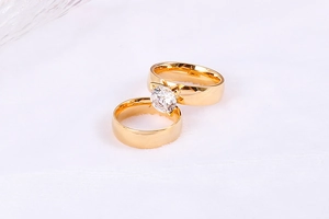 Macro shot of gold couple rings featuring a four-prong round zircon and smooth band